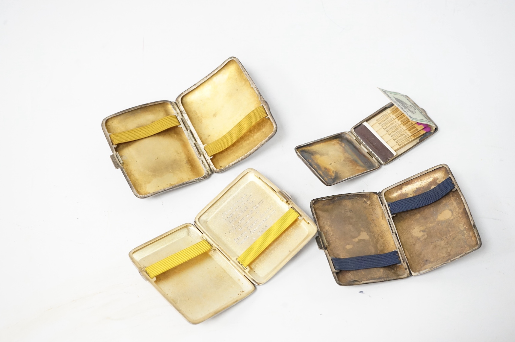 Three assorted George V silver cigarette cases and a silver matchbook case. Condition - fair